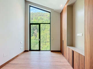 This is an interior of a modern property featuring a large, triangular window with scenic views of lush greenery.
