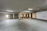 Discover this versatile commercial space featuring an open layout with modern tile flooring, a sleek glass-enclosed office area, and convenient garage door access.