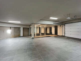 Discover this versatile commercial space featuring an open layout with modern tile flooring, a sleek glass-enclosed office area, and convenient garage door access.