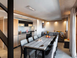 This stunning apartment boasts a spacious open-plan living area with a large dining table perfect for gatherings, a fully equipped modern kitchen, and a cozy living room with comfortable seating.