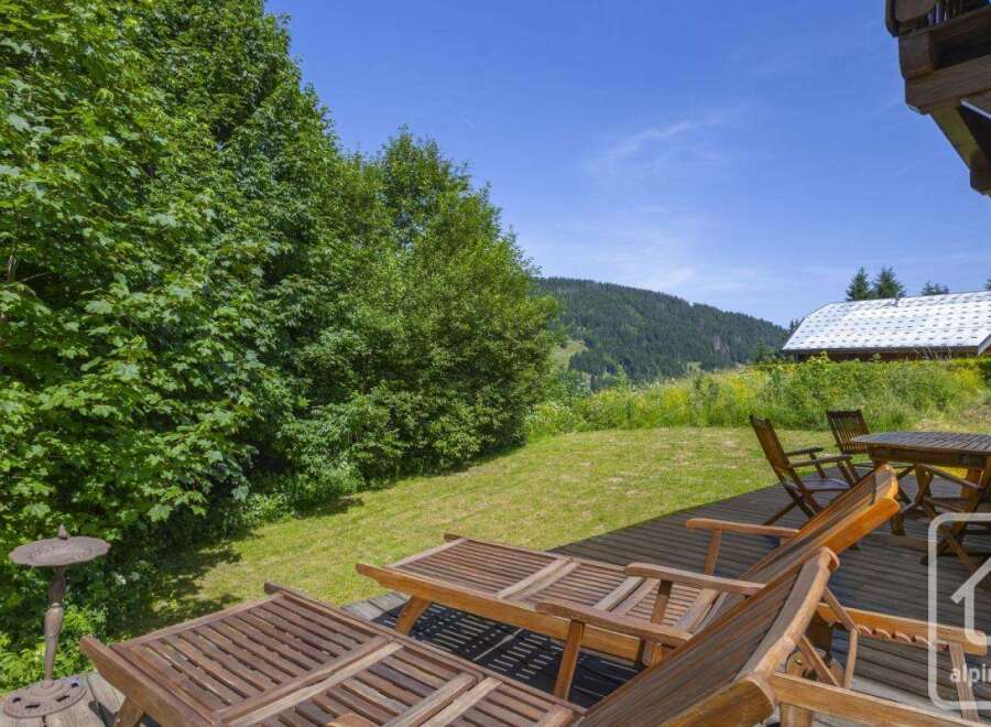 Escape to this serene property boasting a spacious wooden deck with comfortable lounge chairs, perfect for soaking up the sun.