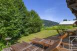 Escape to this serene property boasting a spacious wooden deck with comfortable lounge chairs, perfect for soaking up the sun.