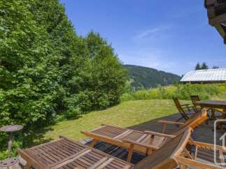 Escape to this serene property boasting a spacious wooden deck with comfortable lounge chairs, perfect for soaking up the sun.