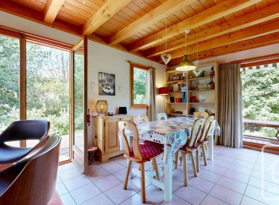 Discover a charming dining area with wood-beamed ceilings and abundant natural light streaming through large windows.