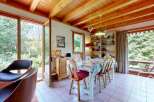 Discover a charming dining area with wood-beamed ceilings and abundant natural light streaming through large windows.