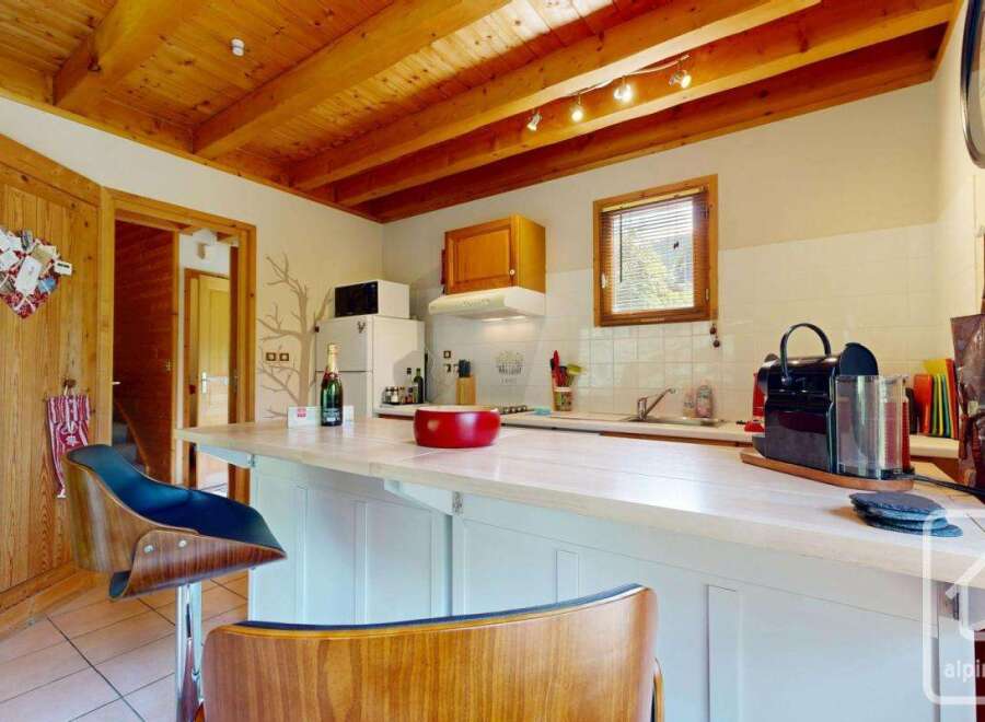 This kitchen boasts a charming rustic design with a wooden beamed ceiling and stylish bar stools.