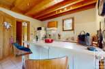 This kitchen boasts a charming rustic design with a wooden beamed ceiling and stylish bar stools.