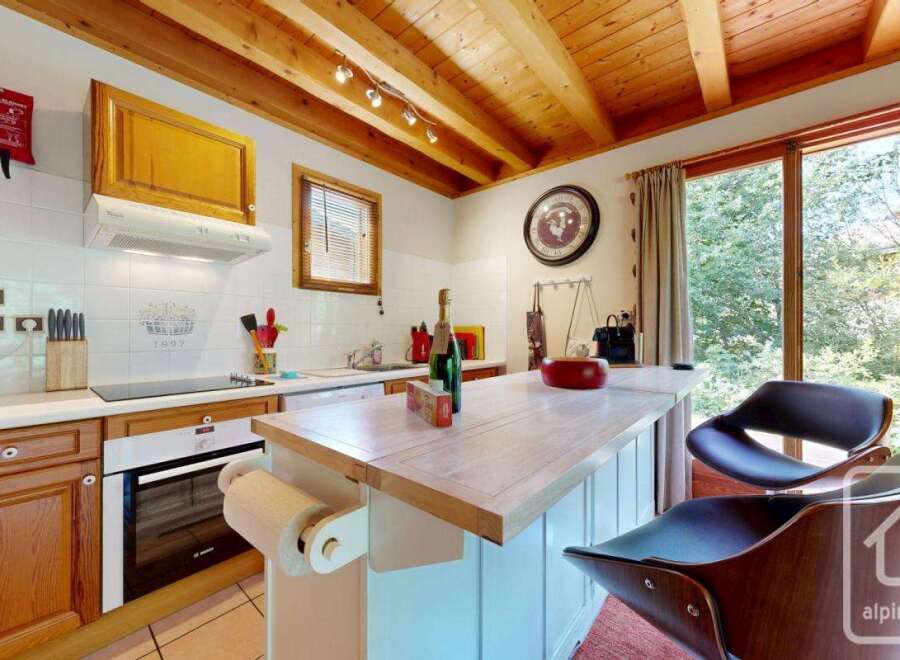 Step into this charming kitchen featuring warm wooden cabinets, a functional island with seating, and abundant natural light streaming through the expansive window.
