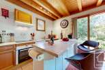 Step into this charming kitchen featuring warm wooden cabinets, a functional island with seating, and abundant natural light streaming through the expansive window.