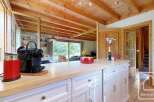 This kitchen features a bright and airy space with white cabinets, light wood countertops, and a rustic wood ceiling.