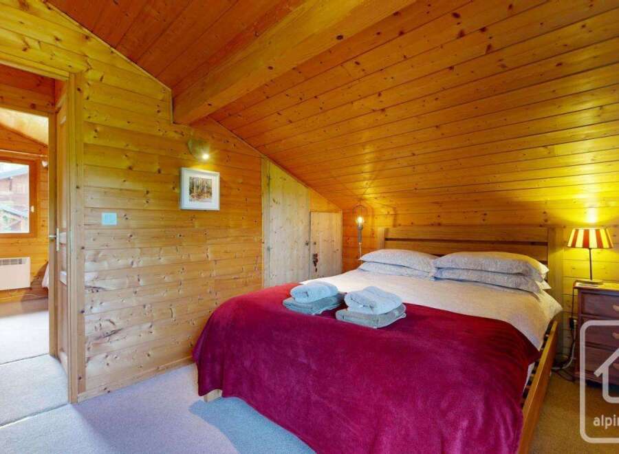 This cozy bedroom features warm wood paneling on the walls and ceiling, creating a rustic and inviting atmosphere.