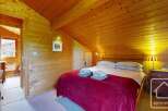 This cozy bedroom features warm wood paneling on the walls and ceiling, creating a rustic and inviting atmosphere.