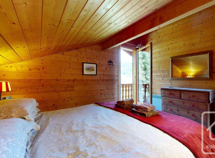 Experience the cozy charm of this alpine bedroom, featuring wood-paneled walls and ceiling that create a warm and inviting atmosphere.