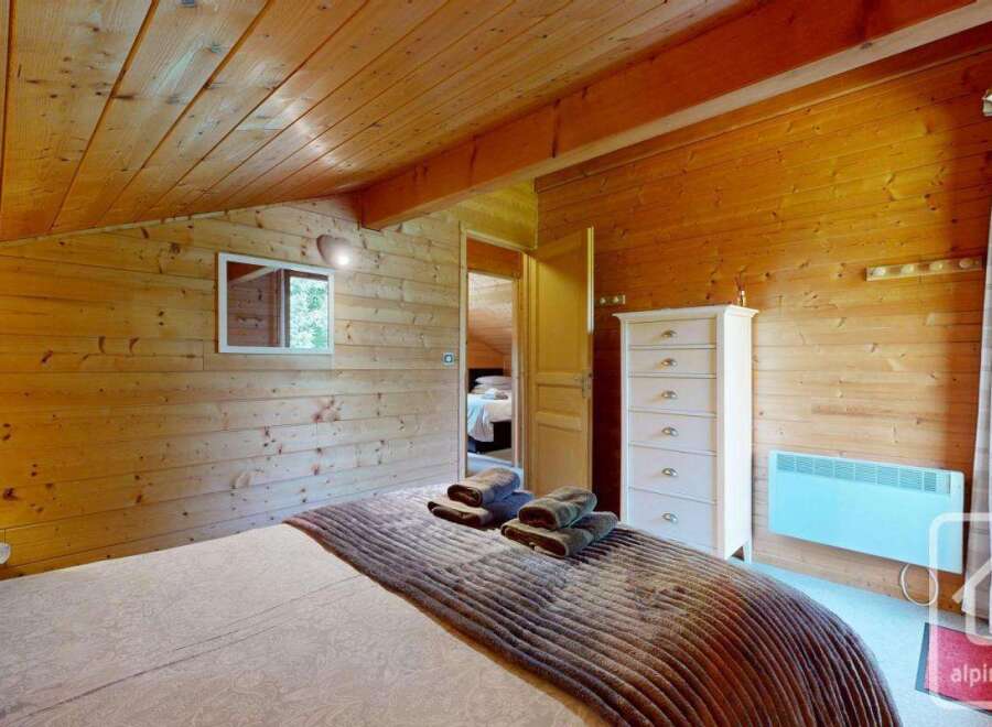 Escape to this cozy chalet bedroom featuring warm wood paneling on the walls and ceiling, creating an inviting, rustic ambiance.