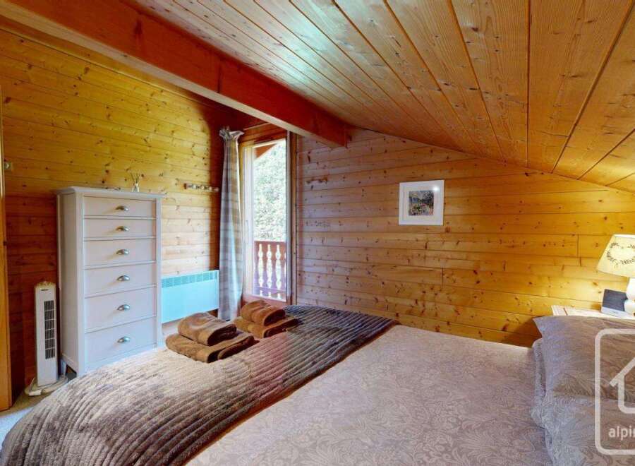 A cozy bedroom with wooden walls and ceiling offers a warm, rustic ambiance.