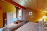 A cozy bedroom with wooden walls and ceiling offers a warm, rustic ambiance.