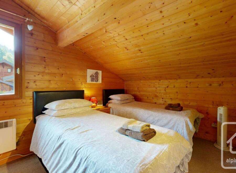 This charming bedroom features warm, wood-paneled walls and ceiling, creating a cozy, rustic atmosphere.