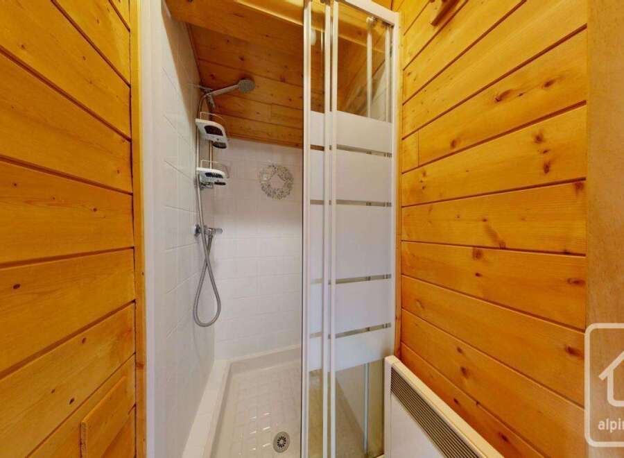 This bathroom showcases a sleek shower stall with sliding doors, complemented by wood-paneled walls that add warmth and character.