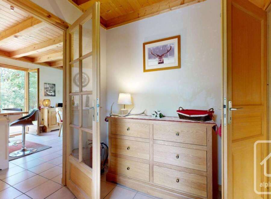 Discover a charming chalet hallway featuring wooden accents, including a dresser and doors that add warmth and character.