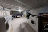 This is a functional basement laundry area with a washing machine.
