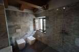 This stylish bathroom boasts stone tile walls and dark flooring for a modern and sophisticated look.
