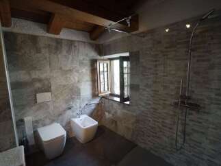 This stylish bathroom boasts stone tile walls and dark flooring for a modern and sophisticated look.
