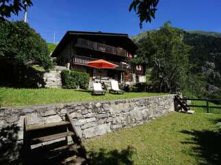 Escape to this charming Swiss chalet nestled in the mountains, boasting a stone facade and multiple balconies.