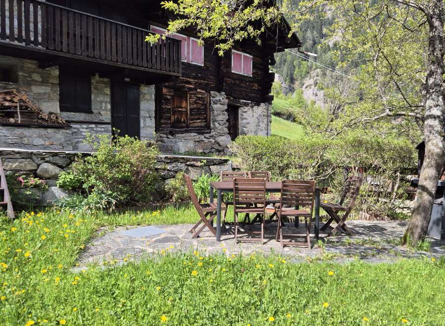 Nestled in a serene landscape, this charming stone and wood chalet boasts a delightful outdoor dining area.