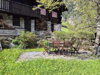 Nestled in a serene landscape, this charming stone and wood chalet boasts a delightful outdoor dining area.