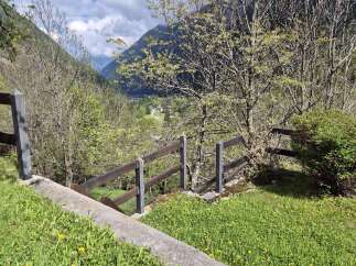 Discover a serene property with stunning mountain views, surrounded by lush greenery and a charming wooden fence.