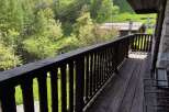 Escape to tranquility with this charming property featuring a wooden balcony overlooking a lush green landscape.