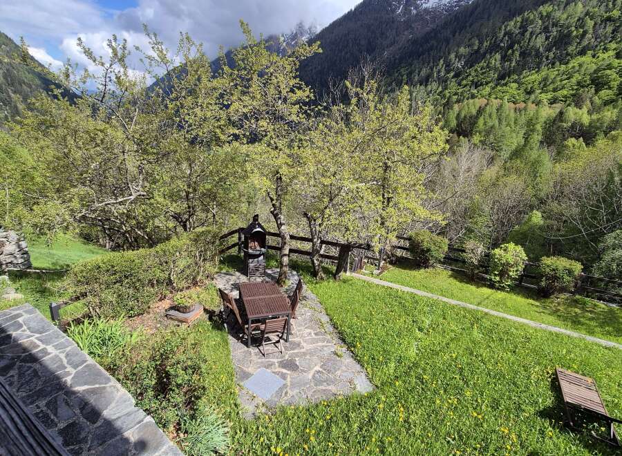 Nestled in a serene mountain setting, this property boasts a charming outdoor dining area with a barbecue, perfect for entertaining.