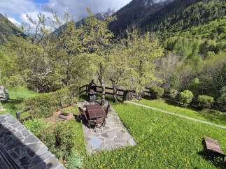 Nestled in a serene mountain setting, this property boasts a charming outdoor dining area with a barbecue, perfect for entertaining.