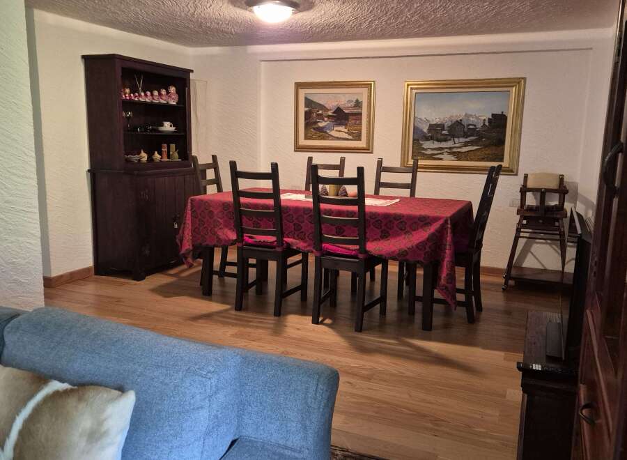 This inviting dining area features a classic wooden table adorned with a patterned red tablecloth, complemented by matching chair cushions.