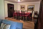 This inviting dining area features a classic wooden table adorned with a patterned red tablecloth, complemented by matching chair cushions.