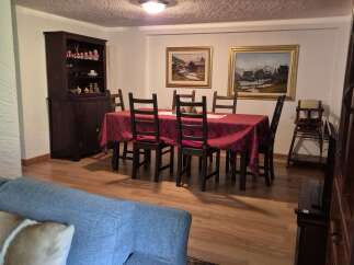 This inviting dining area features a classic wooden table adorned with a patterned red tablecloth, complemented by matching chair cushions.