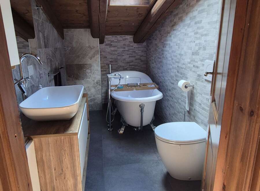 This bathroom features a rustic design with a wooden ceiling and beams, complemented by a skylight that brings in natural light.