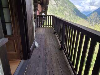 Charming balcony with wooden floor and railing offering stunning mountain views.