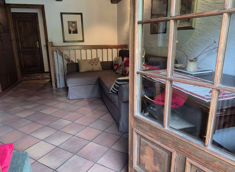 Discover a charming living space with rustic wooden beams overhead, complemented by warm-toned tile flooring that adds character to the room.