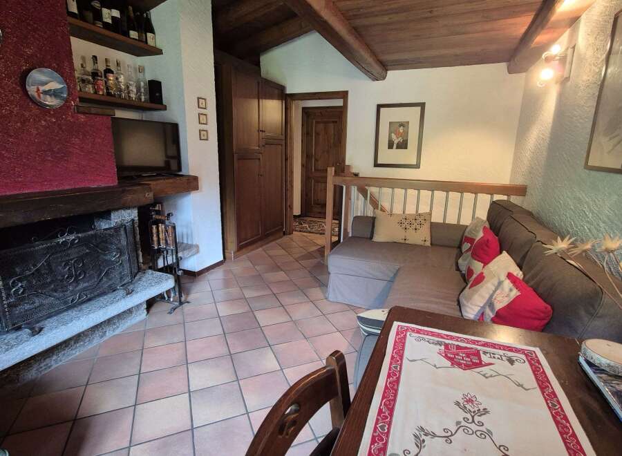 This inviting living room boasts a rustic charm with its exposed wooden beams and stone fireplace.