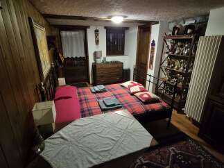 This cozy bedroom features rustic wood paneling, a comfortable plaid bed, and antique furnishings, creating a warm and inviting atmosphere.