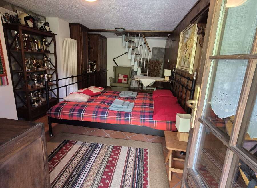 Charming bedroom featuring a cozy, red-toned plaid bed and rustic wooden accents.
