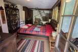 Charming bedroom featuring a cozy, red-toned plaid bed and rustic wooden accents.