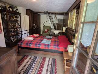 Charming bedroom featuring a cozy, red-toned plaid bed and rustic wooden accents.