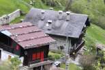 Nestled in a lush, green hillside, this charming alpine property features traditional architecture with stone and wood elements.
