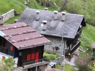 Nestled in a lush, green hillside, this charming alpine property features traditional architecture with stone and wood elements.