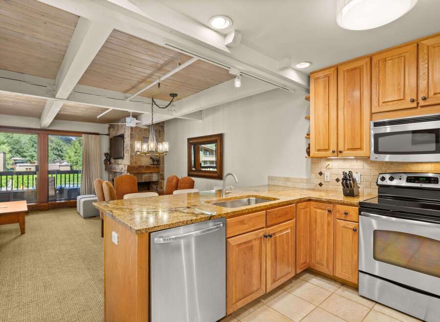 Step inside this inviting kitchen featuring warm wood cabinetry, granite countertops, and stainless steel appliances, perfect for culinary enthusiasts.