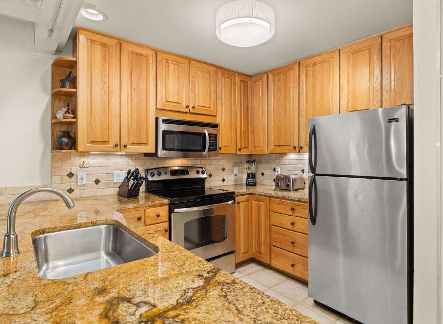 This well-maintained kitchen features warm wood cabinetry, stainless steel appliances, and stunning granite countertops, providing both style and functionality.