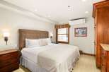 This bedroom features a king-size bed with a padded headboard, bedside tables with lamps, and a built-in wardrobe.