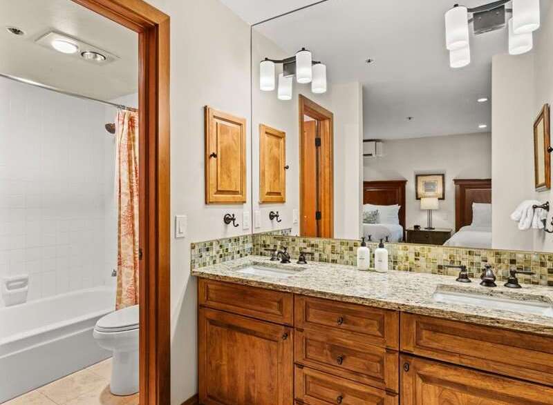 This bathroom features a double sink vanity with granite countertops and warm wood cabinetry.